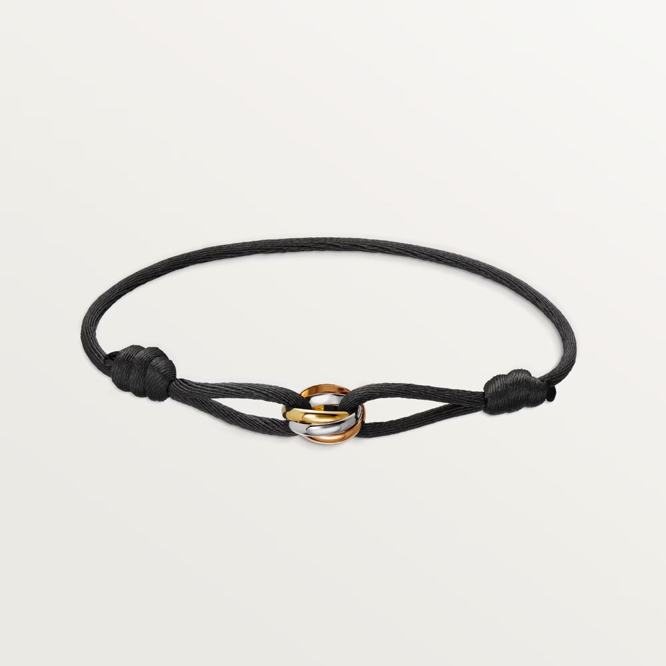 Cartier Trinity bracelet with a black cord and three interlocking white, yellow, and rose gold rings